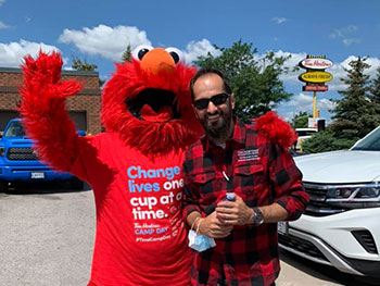 Elmo costume and Volunteer posing for a photo